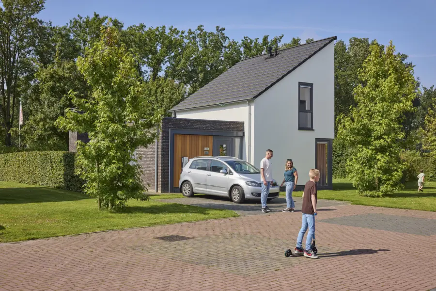 Gezin voetbalt op de parkweg tussen de vakantiehuizen van Recreatiepark de Leistert in Roggel
