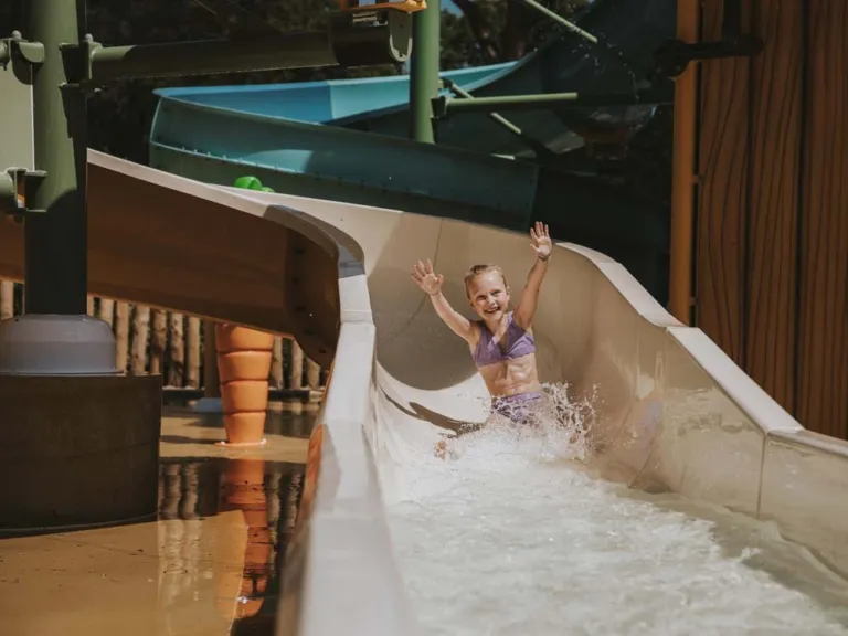 Meisje komt met opgestoken handen van de waterglijbaan af op Beerze Bulten