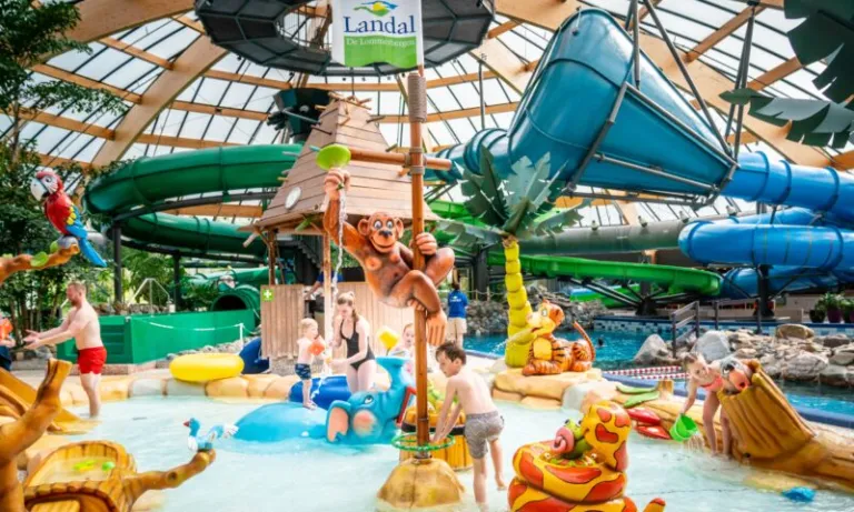 Kinderen spelen bij de waterspeeltuin en de glijbanen in het subtropisch zwemparadijs van Landal De Lommerbergen