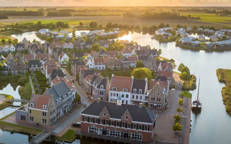 Luchtfoto van Landal Esonstad bij zonsondergang, met de Hollandse gevelhuizen, het vaarwater en de jachthaven