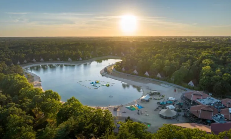 Luchtfoto van de recreatieplas met zandstrand en waterspeeltoestel op Landal Landgoed 't Loo