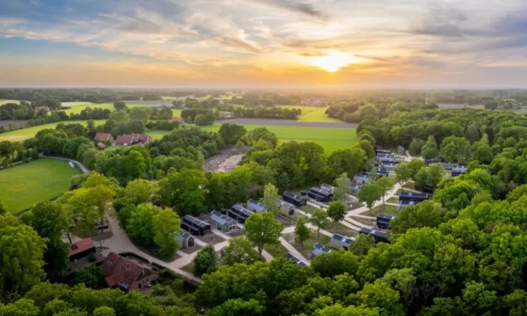Luchtfoto bij zonsondergang van de vakantiehuizen tussen de bomen op Landal Olde Kottink in het Dinkeldal