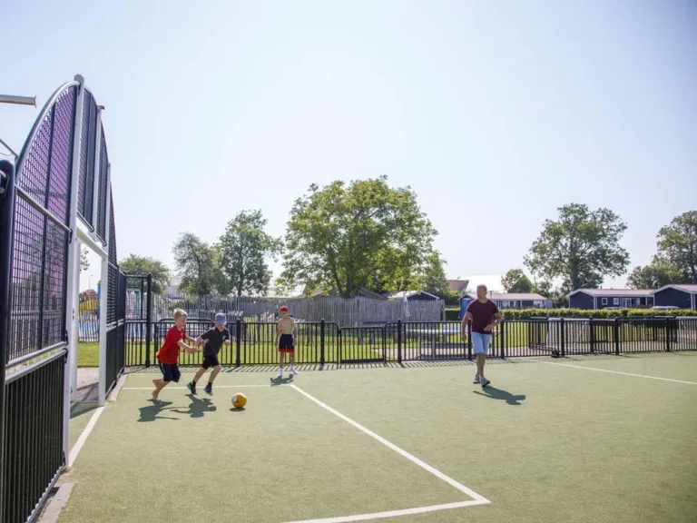 Voetballen op het omheinde multisportveld van Camping Zonneweelde