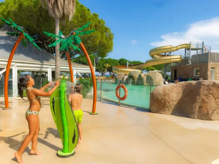 Kinderen hebben plezier bij de watersproeiers bij camping Arinella Bianca