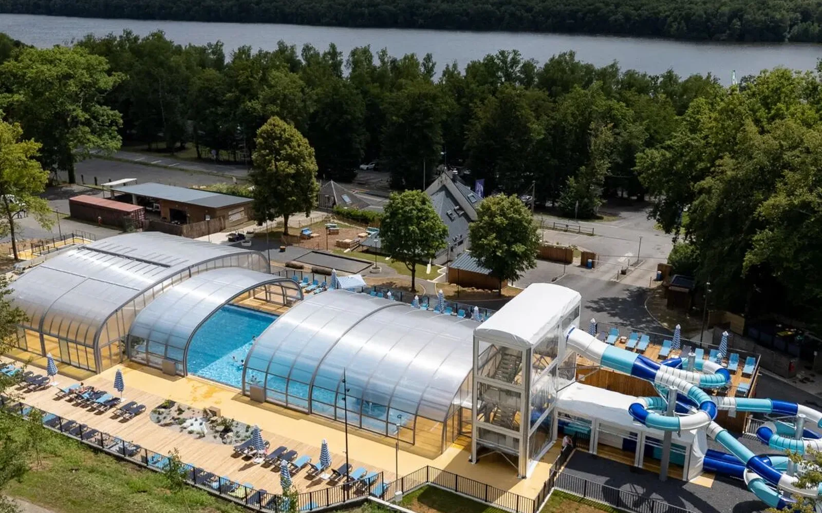 Overzicht zwembad met glijbanen en ligplaatsen op camping Le Lac des Vieilles Forges