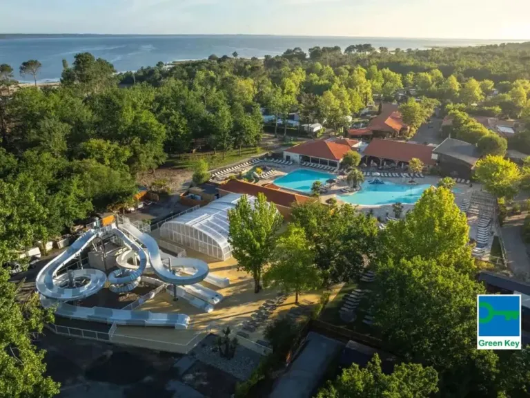 Overzicht van zwembad met glijbaan en de zee in de verte op camping Mayotte Vacances